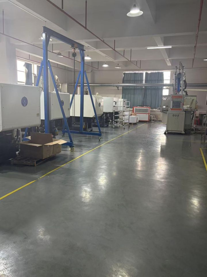 Injection-moulding hall with machines under blue gantry cranes.