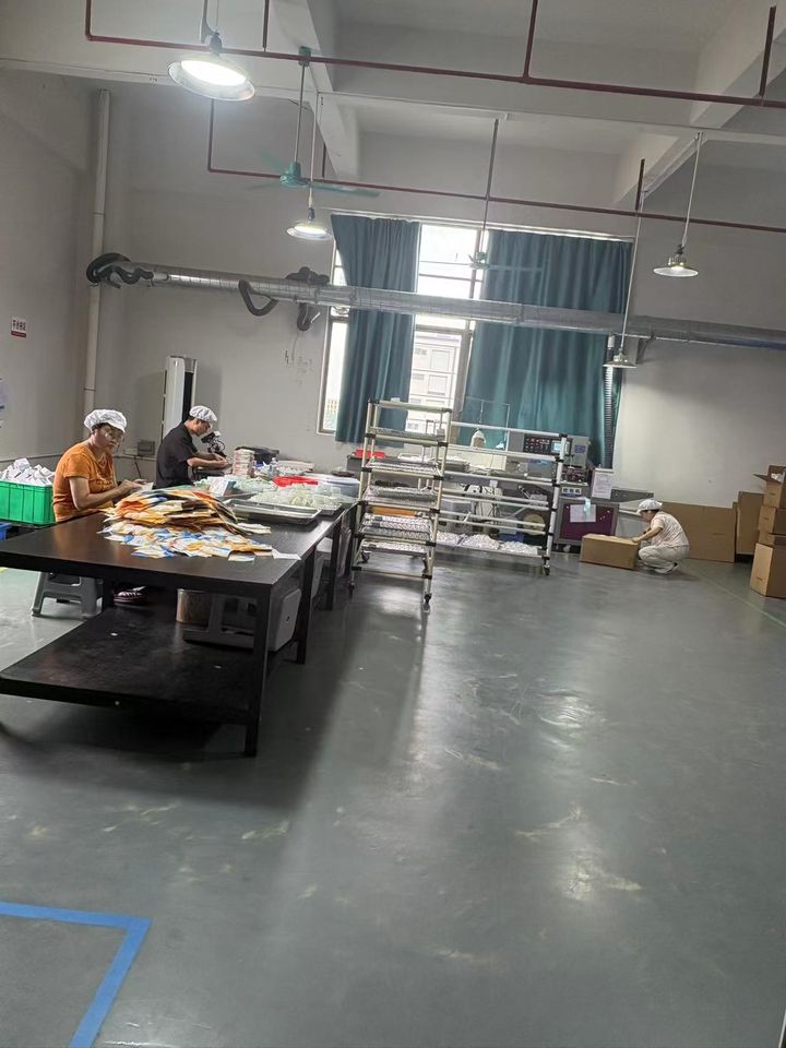 Packing hall: printed pouches on a black table and a sealing machine.